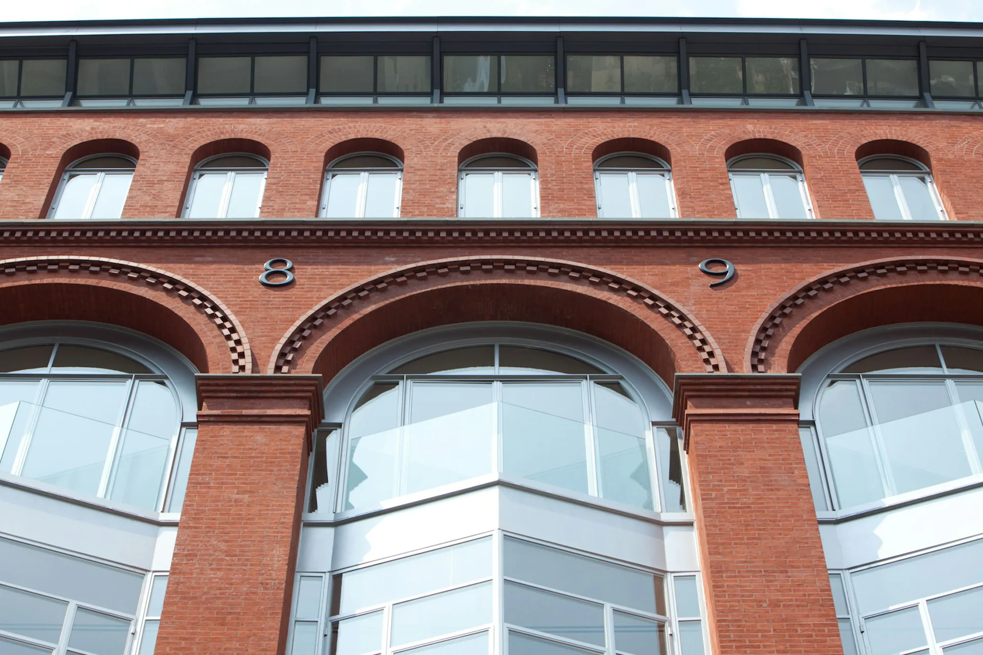 Restored brick facade with arched windows and ornamental detailing, featuring large multi-pane windows and decorative brickwork by TRA studio Architecture PLLC, New York City.