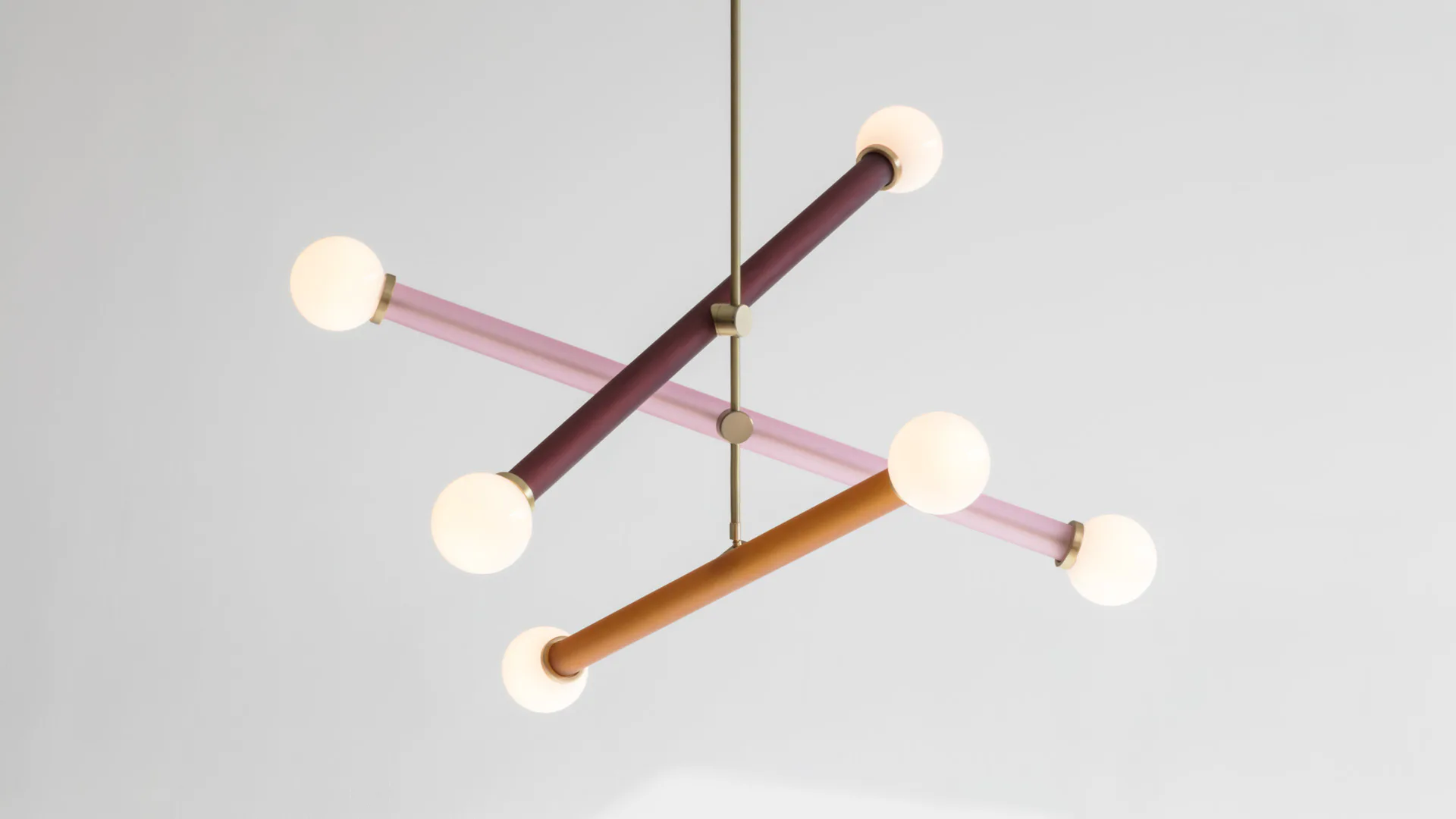 Abstract mobile sculpture with wooden rods in burgundy, pink, and orange suspended from a central axis, with cream-colored spheres at endpoints, by Trueing.