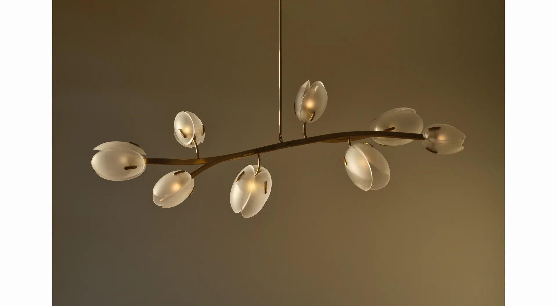 Sculptural pendant lighting fixture with organically-shaped glass discs suspended from branching bronze armature against warm neutral backdrop by Trueing.