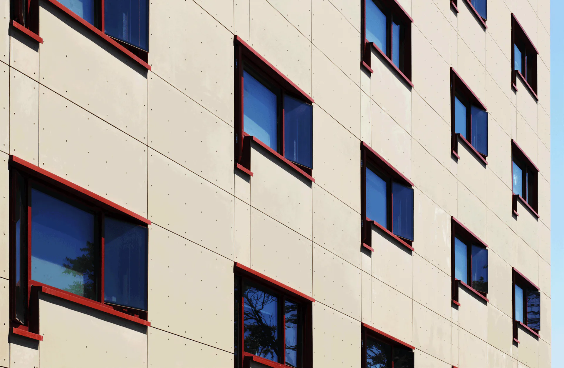 Cream-colored residential facade with regular window pattern and red-brown frames, photographed by Urban Architectural Initiatives.