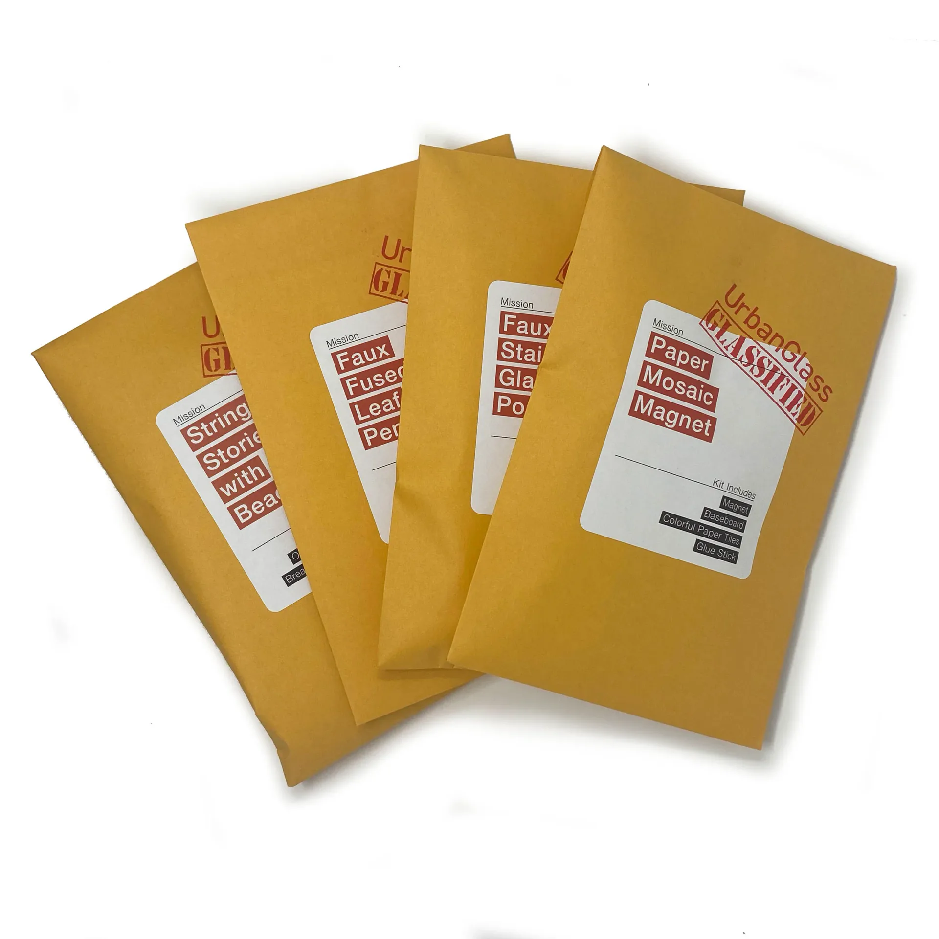 Four golden kraft mailer envelopes with red stamped address labels arranged in a fanned display, a packaging design project by UrbanGlass.