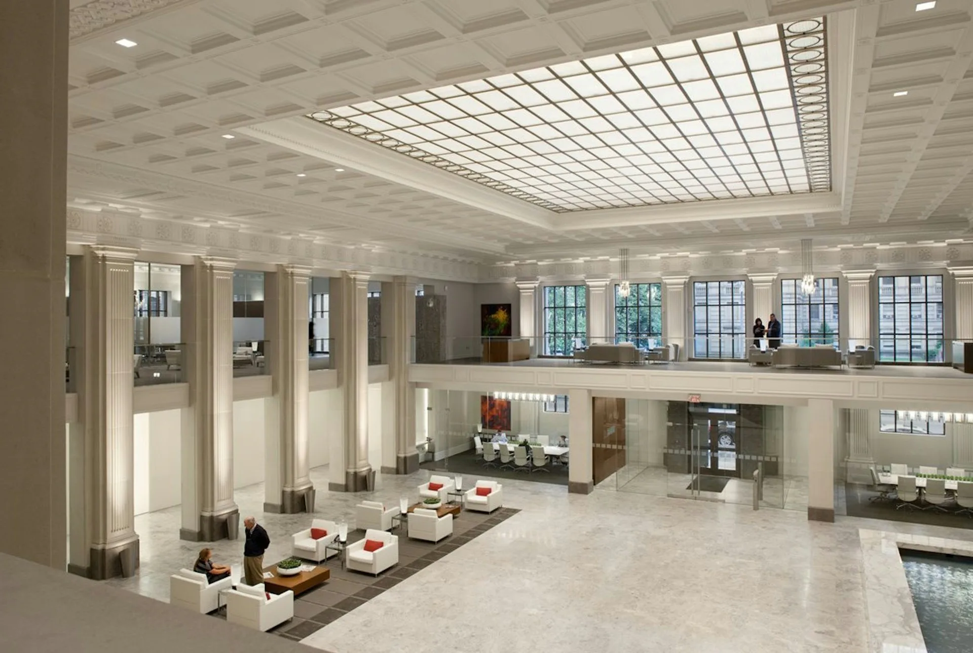 Bright modern lobby with coffered ceiling, columns, and multi-level galleries overlooking a polished floor atrium by Vocon.