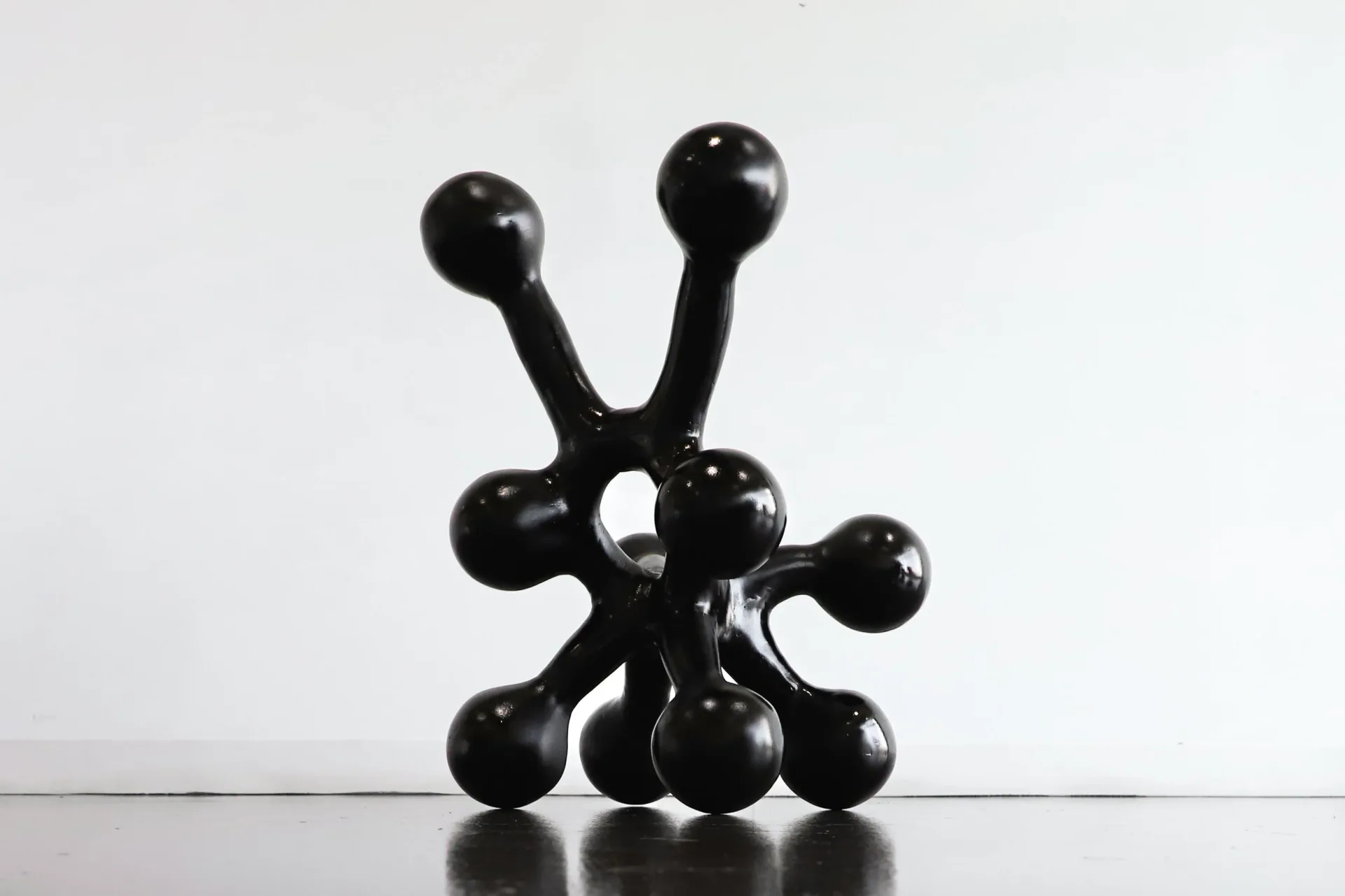 Black spherical sculptural installation with interconnected stems and bulbous forms arranged on a white surface by Voidfill Studio.
