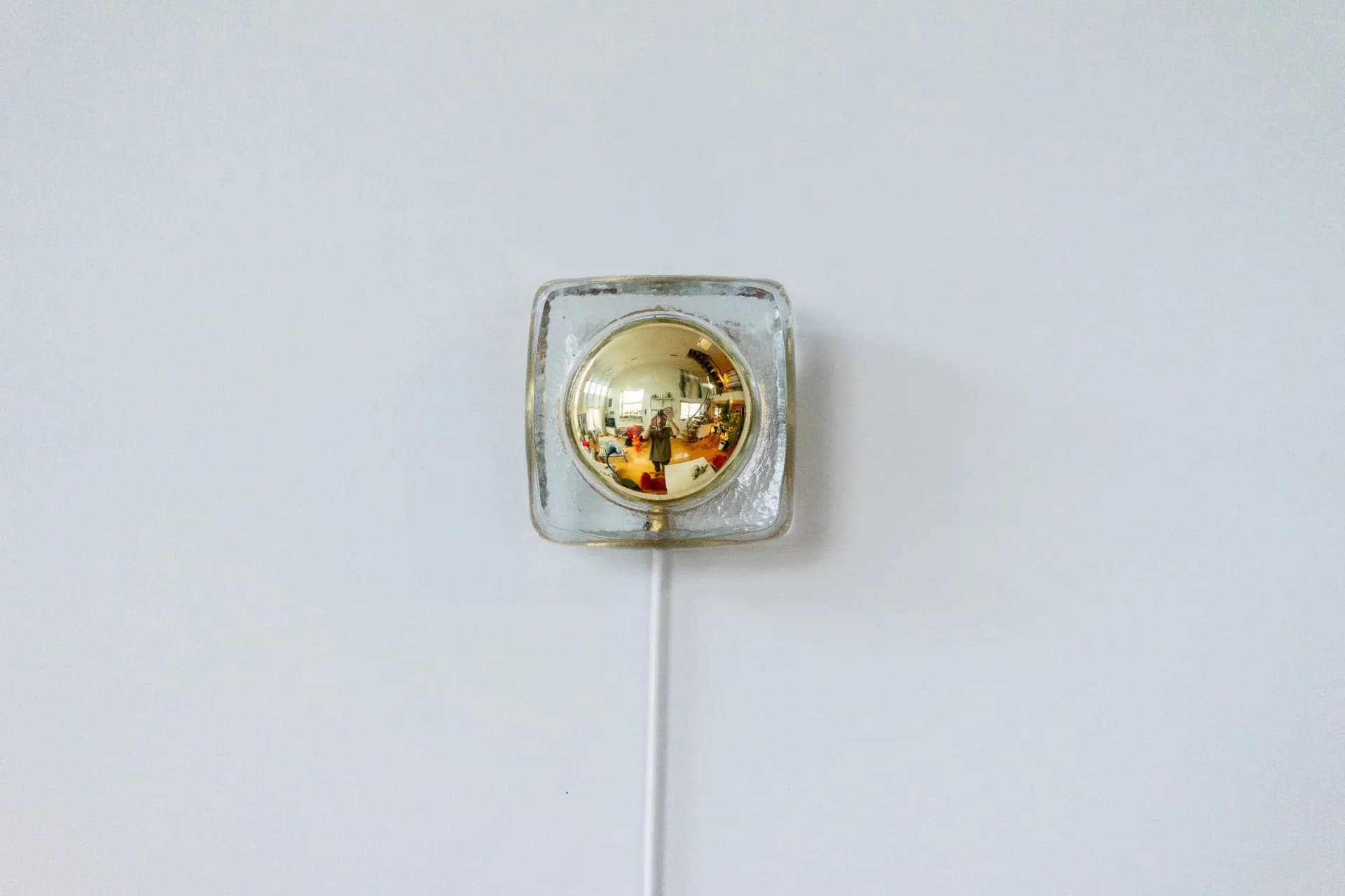 Minimalist wall-mounted light fixture with frosted glass square housing and brass-toned spherical bulb by Voidfill Studio.