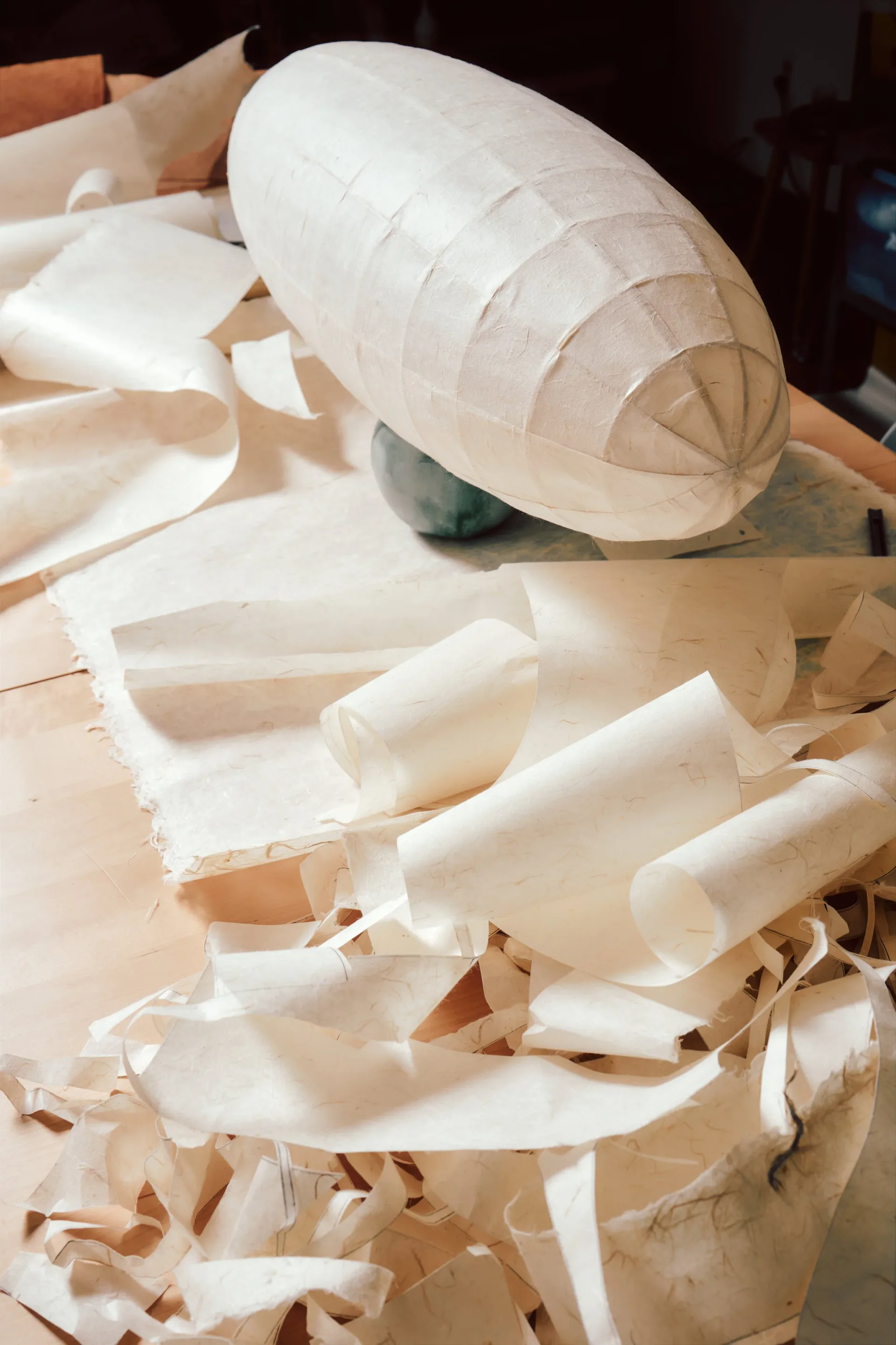 White paper model with curved, layered sections on wooden base, demonstrating architectural design concept and material exploration by Vy Voi.