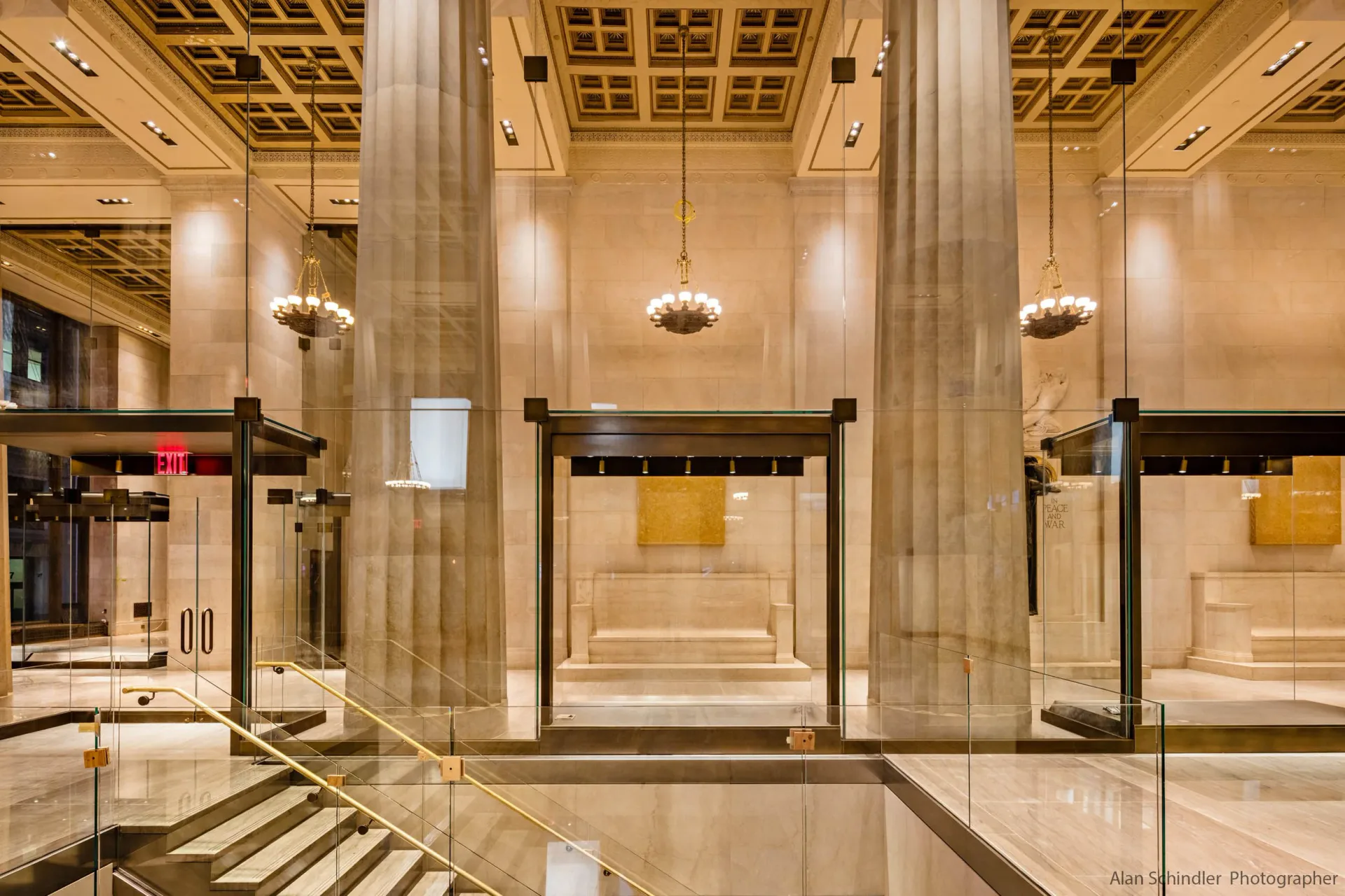 Grand marble lobby with soaring columns, coffered ceiling, pendant lighting, and glass storefronts by WALD Studio.