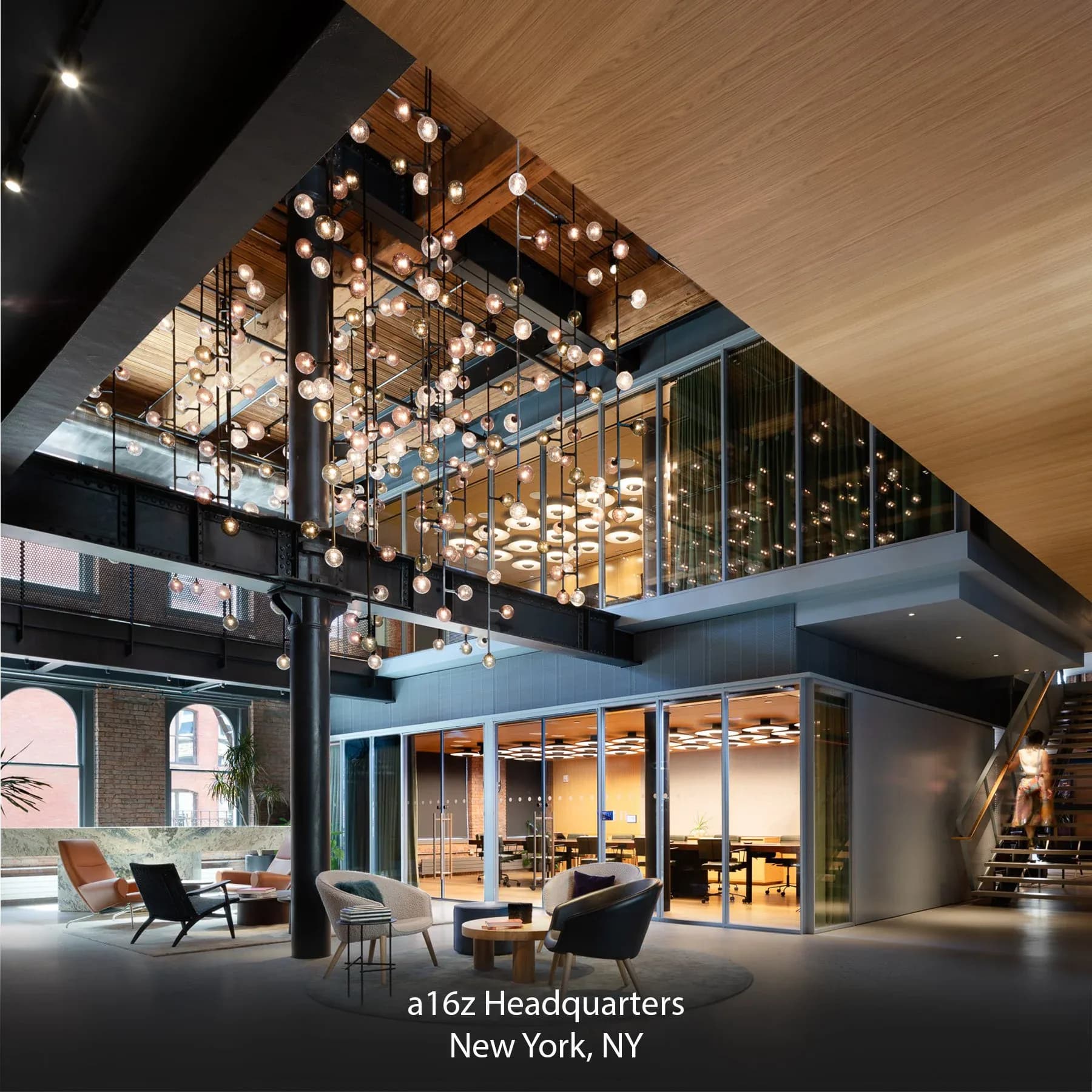 Multi-level modern headquarters with suspended globe lighting fixtures, warm wood ceilings, and floor-to-ceiling glazing by WALD Studio.