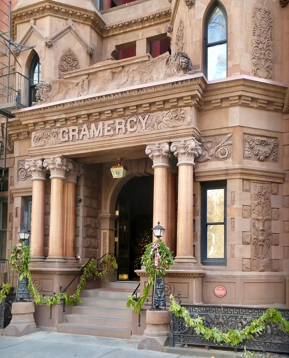 Brownstone facade entrance with ornate Corinthian columns, carved stone detailing, and 'Gramercy' inscription, designed by Walter B. Melvin Architects.