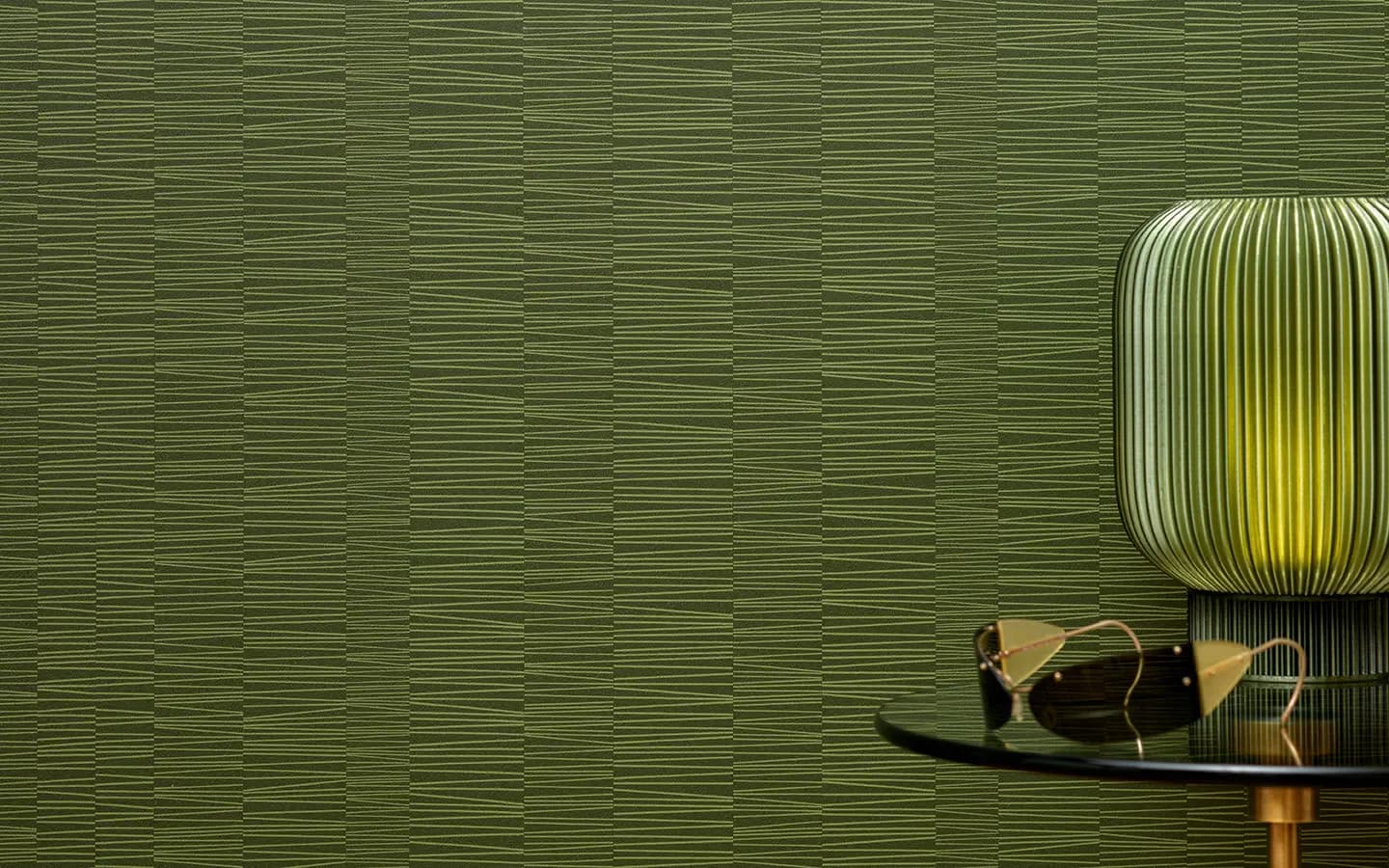 Green textured wall with ribbed surface detail, illuminated cylindrical pendant light fixture, and sculptural wooden furniture element by Wolf-Gordon.