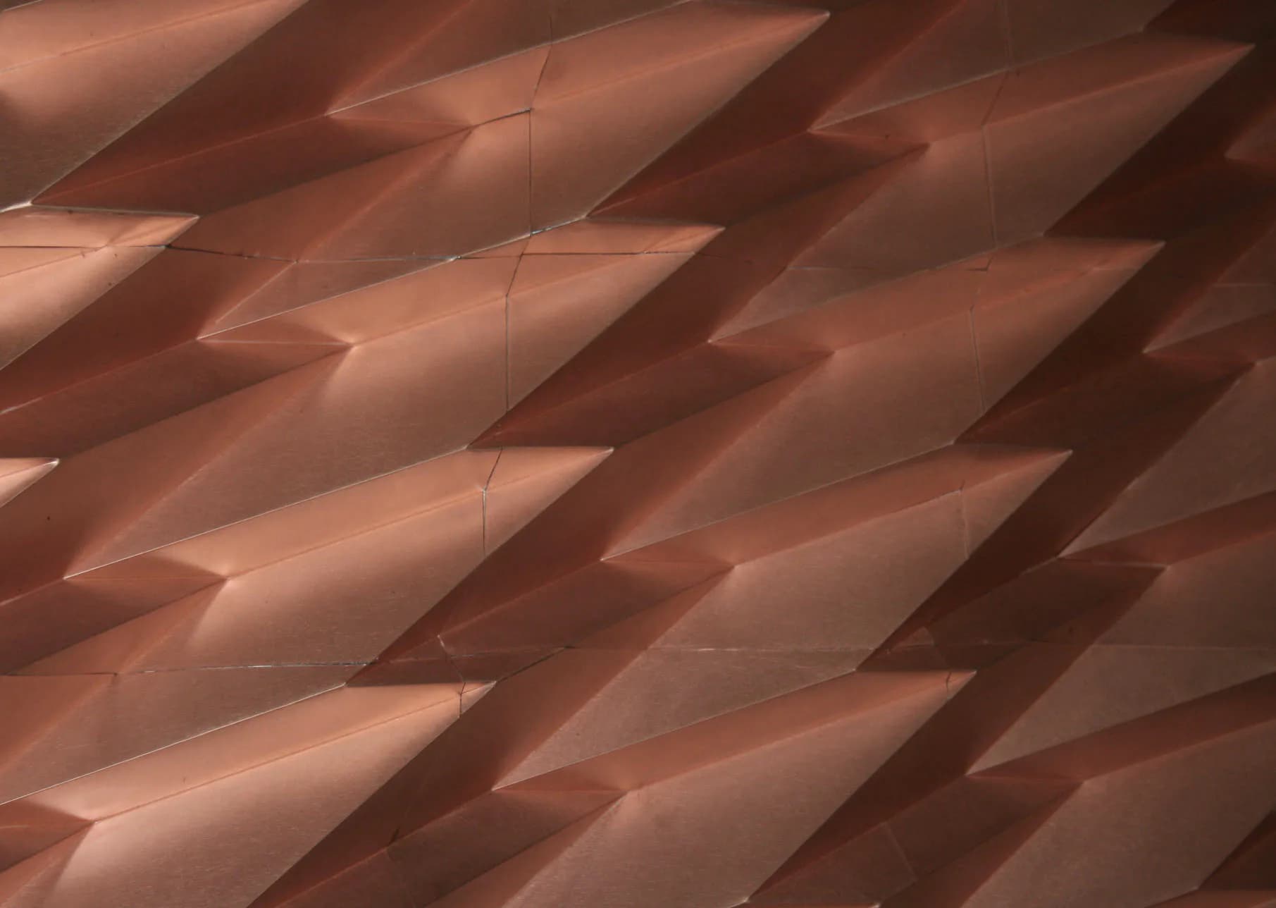 Angled ceiling detail with geometric copper-toned panels and dramatic shadow play by Yoshihara McKee Architects.