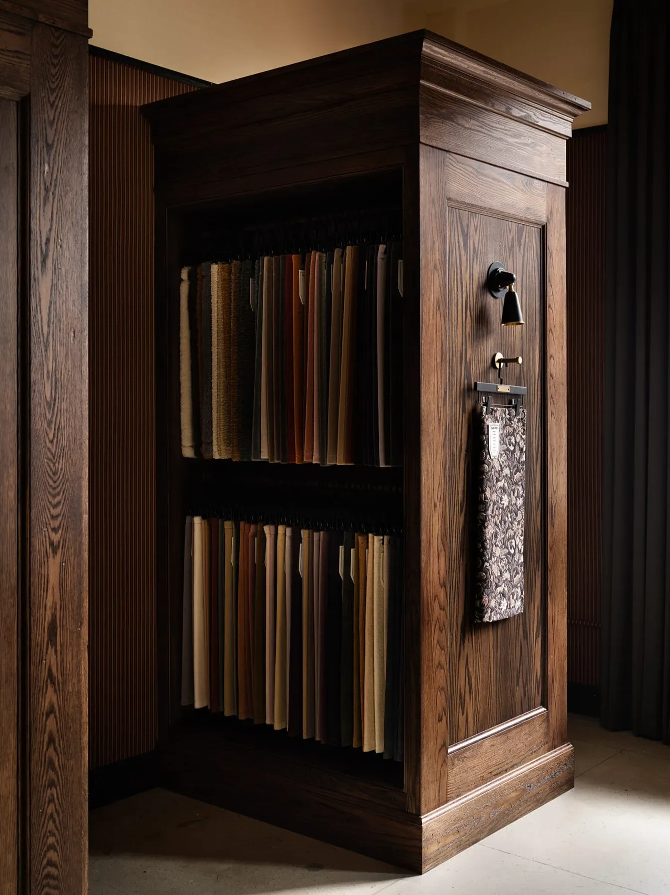 Dark wood display cabinet with glass doors showcasing wood samples and finishes, designed by Zak + Fox.