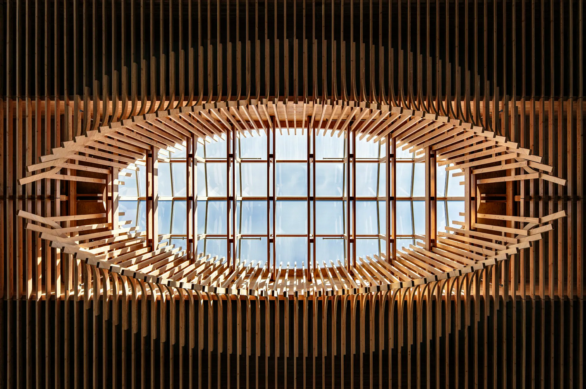 Wooden ceiling structure with radiating slats forming an eye-shaped opening to sky, featuring symmetrical geometric design by ZGF Architects.